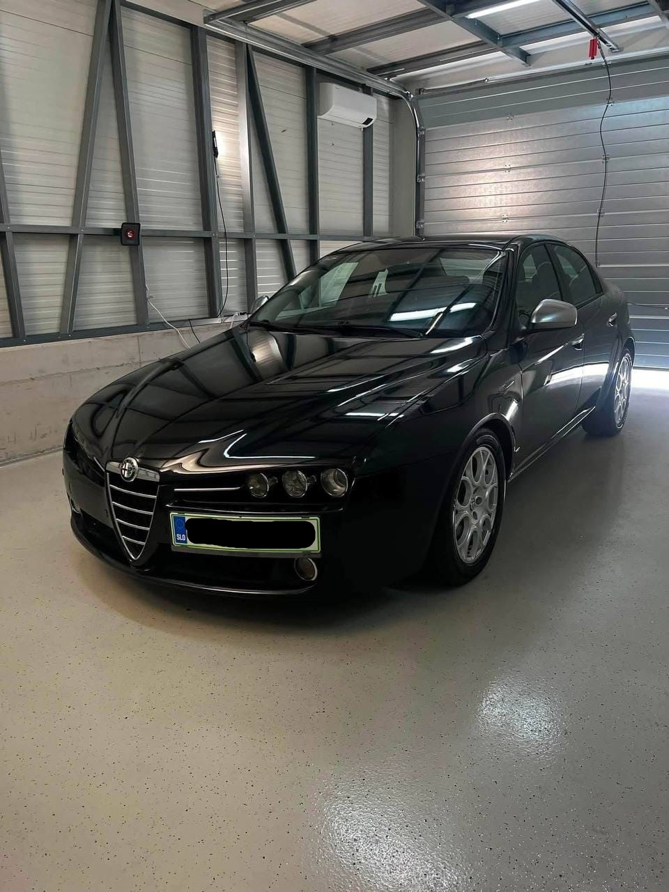 Črna Alfa Romeo 159 s sijočim lakom v garaži