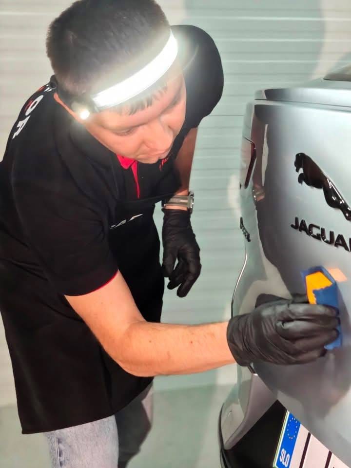 Detailer s čelno svetilko pregleduje lak Jaguarja